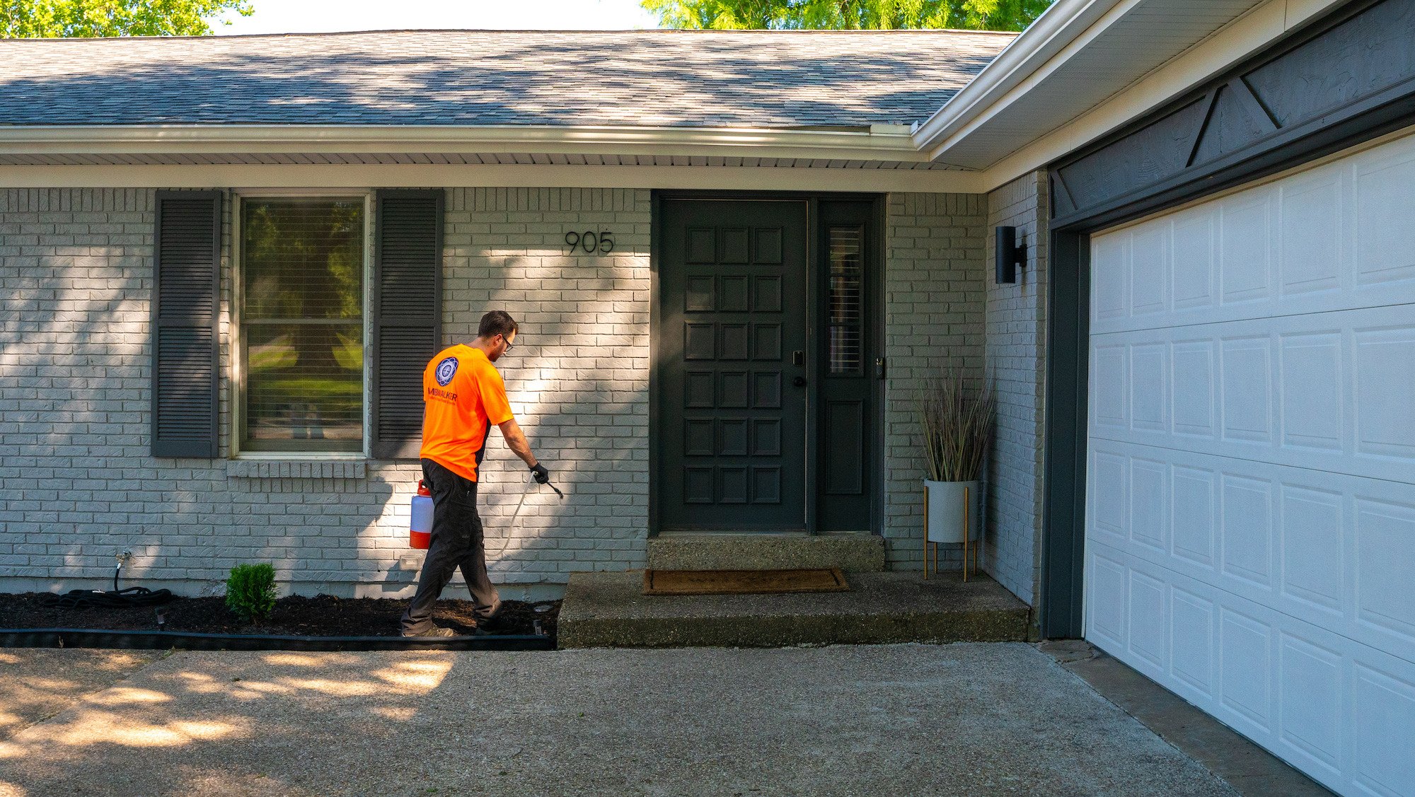 perimeter pest control technician liquid spraying outside of house 1