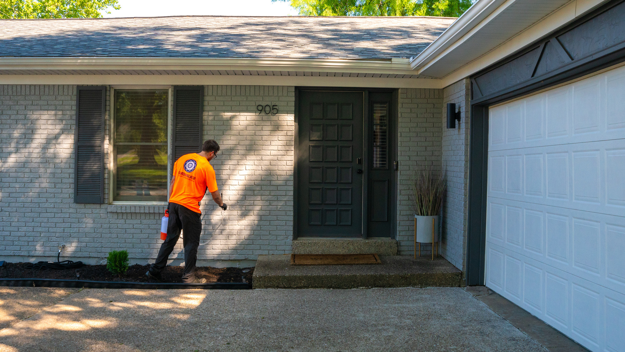 perimeter pest control technician liquid spraying outside of house