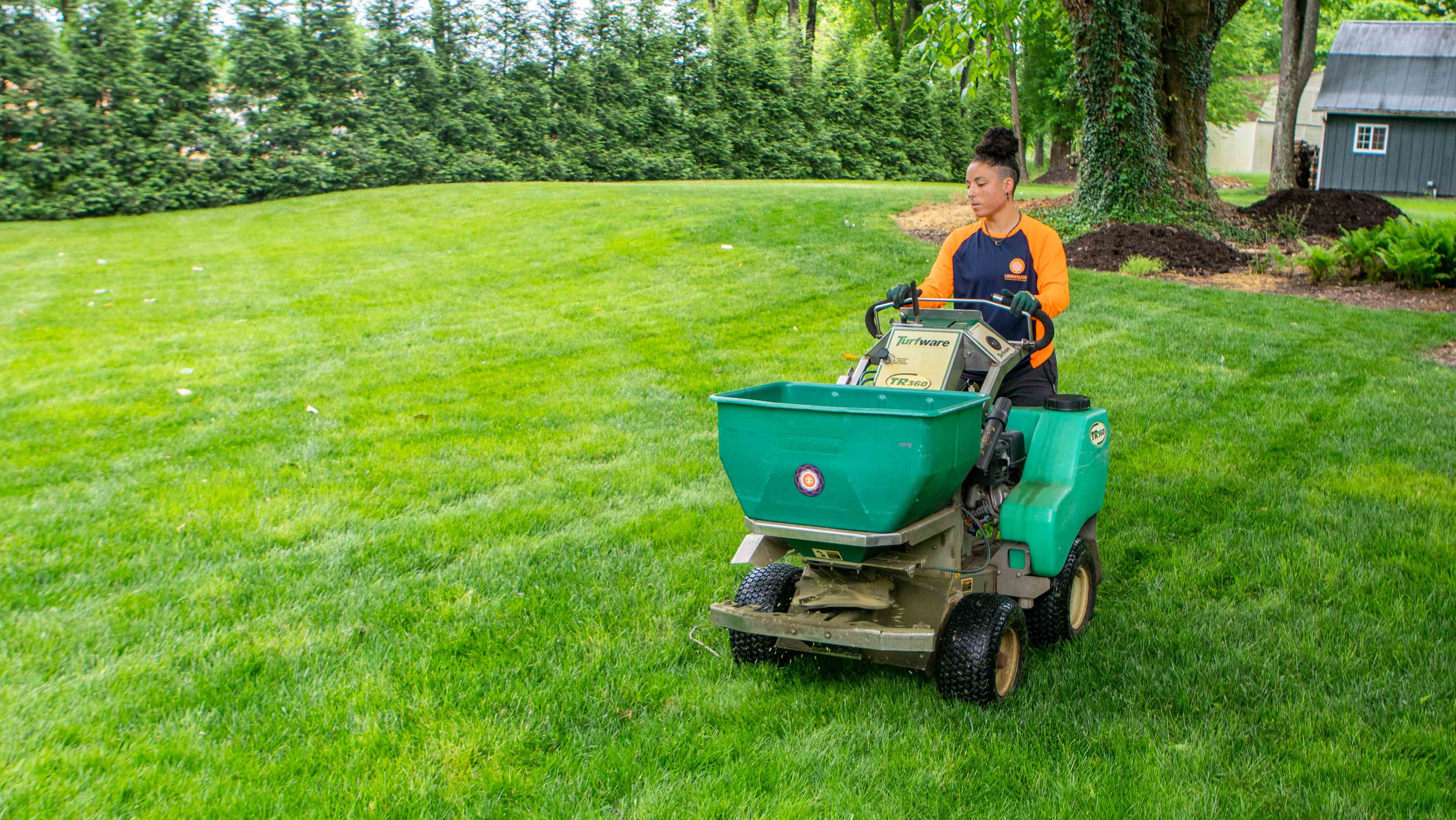 technician on machine applying a fertilizer application on lawn